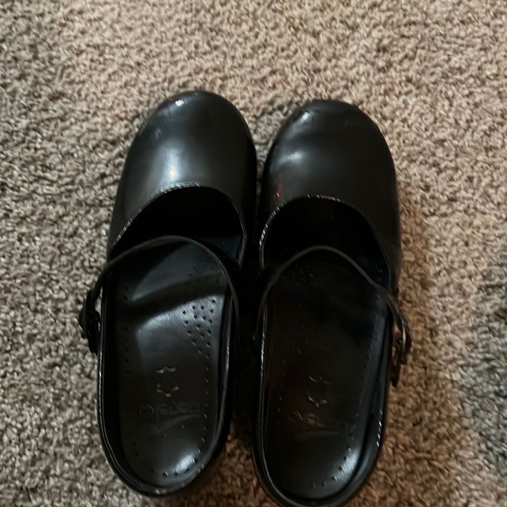 Two pairs of Dansko shoes one pair of Mary Jane the other are multi colored.